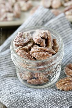 a glass jar filled with nuts on top of a towel next to another bowl full of nuts