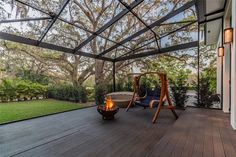 a deck with a swing chair and fire pit