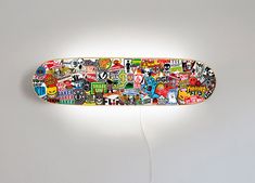 a skateboard with many stickers on it is lit up by a light fixture