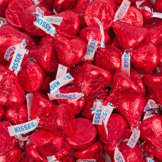 a pile of red heart shaped candies with kisses on them