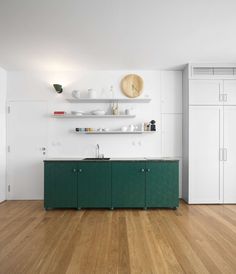 an empty kitchen with green cabinets and white cupboards on the wall, along with wooden flooring