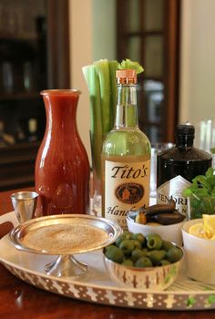 an assortment of olives and other ingredients on a serving platter next to bottles of alcohol