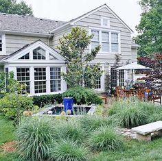 a house with an outdoor dining area in the front yard, and landscaping around it