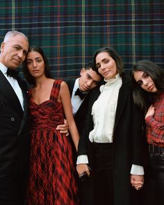 a group of people standing next to each other in front of a tartan wall