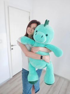 a woman holding a large blue stuffed animal in her arms and smiling at the camera