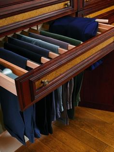 an open drawer in a closet filled with clothes