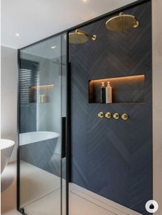 a bathroom with a glass shower door and gold fixtures on the wall, along with a white bathtub