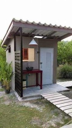 a small shed with a table and sink in the back yard next to a walkway