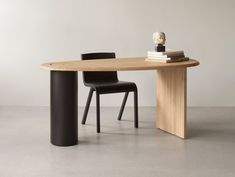 an oval table with two chairs and a book on the top, in front of a white wall