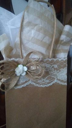 a brown paper bag with white flowers and lace on the handle is sitting on a table