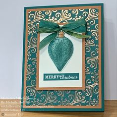 a christmas card with a green ornament hanging from it's side on a table