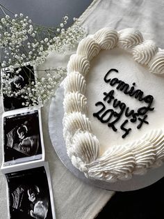 a heart shaped cake sitting on top of a table next to two pictures and flowers