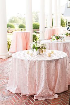 the tables are covered with pink tablecloths and centerpieces for an outdoor wedding