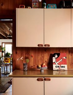 a kitchen with wooden paneling and cabinets in the background, including a painting on the wall