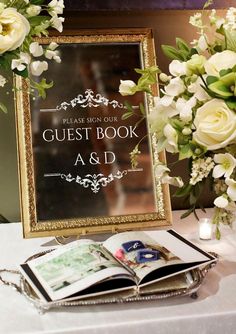 an open book sitting on top of a table next to flowers