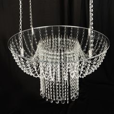 a glass chandelier hanging from chains on a black background