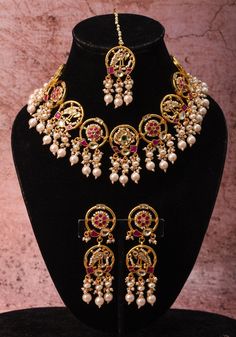 Discover the epitome of elegance and royalty with our Green, White, and Pink necklace set. Perfect for special occasions, this set features our Plenty Pearly Exquisite floral design and peacok Jadau necklace, complete with Dangling Pearls and intricate floral pendant details accented with white beads. The stunning floral and peacock motif adds a touch of opulence to this prominent set. Included are a matching pair of earrings and a maang tikka, completing the luxurious look. Your search for an a Pink Necklace Set, Jadau Necklace Set, Jadau Necklace, Peacock Motif, Maang Tikka, Floral Pendant, Pink Necklace, White Beads, Precious Metals