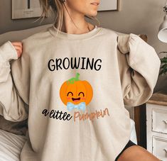 Are you looking for the perfect sweatshirt for Halloween? Our Growing a little Pumpkin sweatshirt is super comfortable and designed to bring joy and excitement to your pregnancy reveal. Embrace the fall season and share the wonderful news with our Fall Baby Reveal Sweater. This cute Thanksgiving Pregnancy Reveal Sweater doubles as a stylish fall maternity t-shirt, making it an ideal gift for expecting parents who want to cherish this special time in their lives. ♥PRODUCTION TIME: 1-5 days (usual Pumpkin Gifts For Parents, Thanksgiving Pregnancy Announcement, Halloween Gender Reveal, Gifts For Expecting Parents, Pumpkin Sweatshirt, Fall Maternity, Pumpkin Sweatshirts, Shirt Making, Expecting Parents