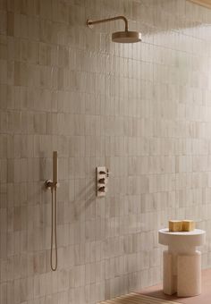 a bathroom with a shower, sink and toilet paper holder on the wall next to it