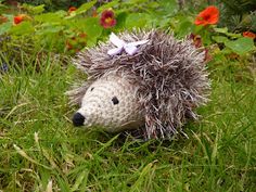 a hedgehog toy sitting in the grass with flowers around it's head and eyes