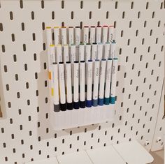 several different colored markers on a white pegboard