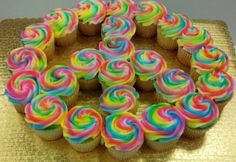 cupcakes decorated with rainbow swirl icing on a table