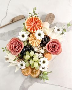 an arrangement of fruits and flowers on a marble surface