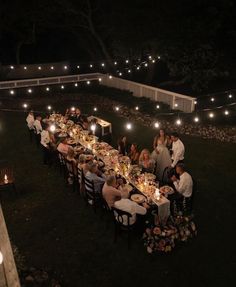 a group of people sitting around a dinner table with candles on the ground in front of them