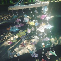 a wind chime hanging from a tree in the sun with lots of butterflies on it