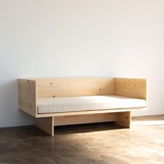 a wooden bench sitting on top of a floor next to a white wall and window