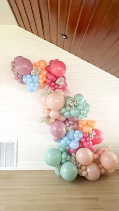 balloons are arranged in the shape of a letter z on a wooden floor next to a white wall