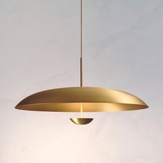 a gold colored pendant light hanging from a ceiling in a room with white walls and flooring