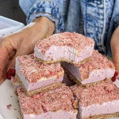 a person holding a white plate with several pieces of cake on top of each other