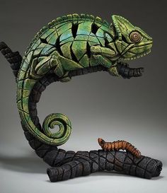 a sculpture of a lizard and a caterpillar on a gray background, with the tail curled up