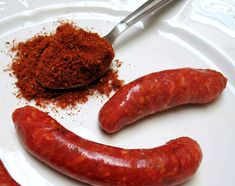 two sausages on a white plate with spices and seasoning next to the hot dog