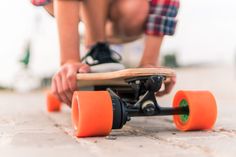 a close up of a person riding a skateboard on the ground with orange wheels