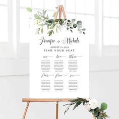 a sign with greenery and flowers on it next to a easel for seating