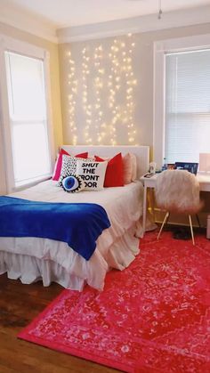 a bedroom decorated in red, white and blue with lights on the wall behind the bed