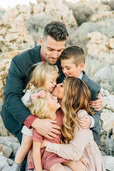 a man and two children hugging each other while standing in front of some rocks with their arms around them