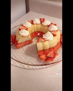 a cake with strawberries and whipped cream is on a glass plate, ready to be eaten