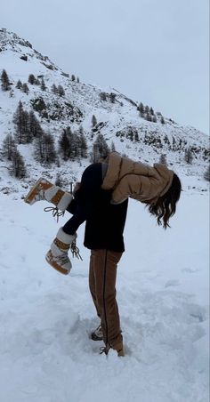 a person doing a handstand in the snow with their skateboard on his feet