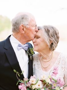 an older couple kissing each other while holding flowers