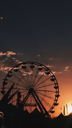 a ferris wheel at sunset with the sun in the background