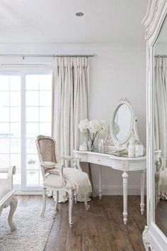 a white bedroom with a large mirror and dressing table in front of a sliding glass door