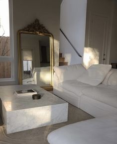 a living room with white furniture and a large mirror