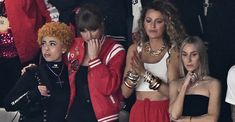 the group of young women are dressed in red and white outfits, while one woman is covering her face with her hands