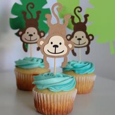 cupcakes with blue frosting and monkeys on top are sitting on a table