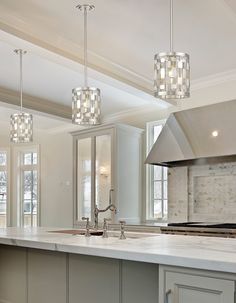 a kitchen with an island and three lights hanging from the ceiling