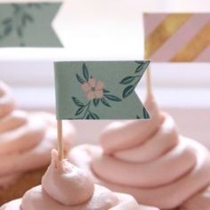 cupcakes with pink frosting and a small flag on top are sitting next to each other