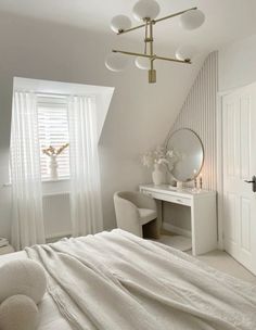 a bedroom with a bed, desk and chair under a slanted ceiling light fixture